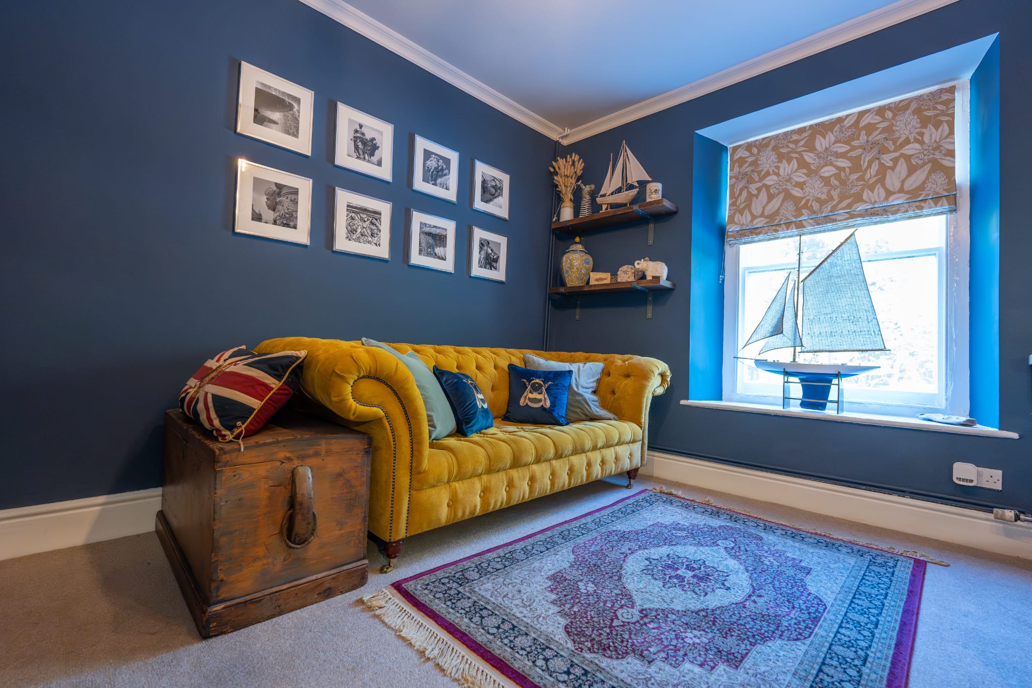 The snug with a yellow velvet sofa and sailing-boat models